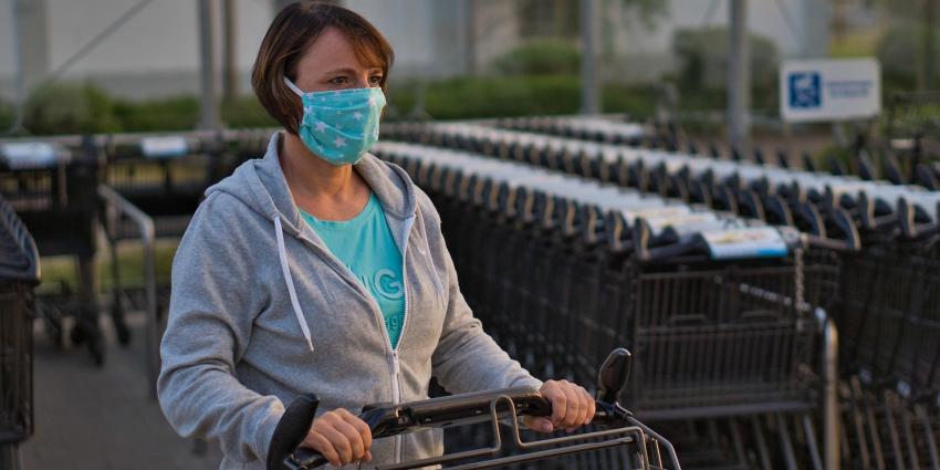 Vrouw met mondkapje en winkelwagen Vrouw met mondkapje en winkelwagen