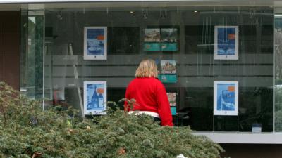 Vrouw bekijkt woningen in etalage Vrouw bekijkt woningen in etalage