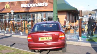 Automobilist rijdt met auto terras McDonald&#039;s op